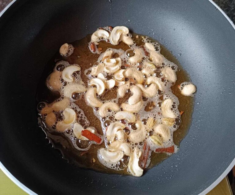 Frying cashews, garam masala spices with oil and ghee in a wok to make veg fried rice