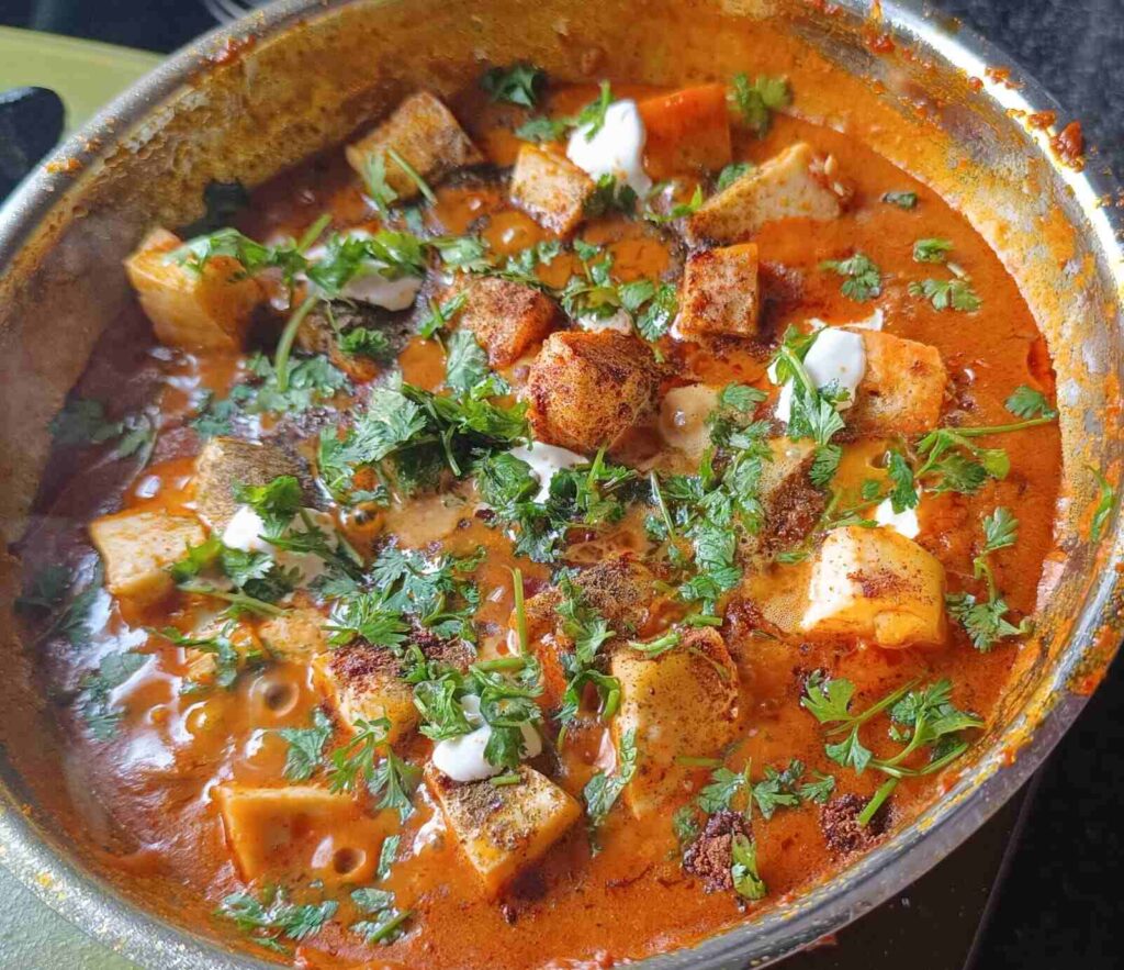 Showing paneer butter masala in a pan. Sprinkled coriander leaves on it