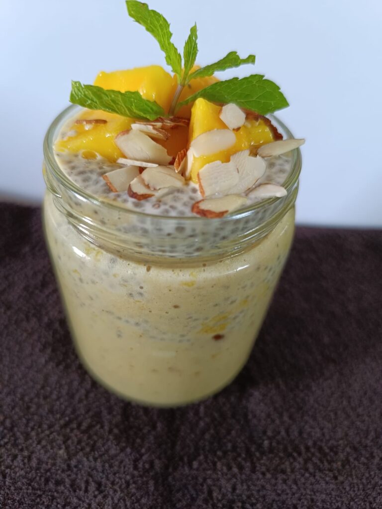 Mango oats smoothie for weight loss recipe, showing in a jar. Garnish with mango cubes, almond flakes and pudina leaves
