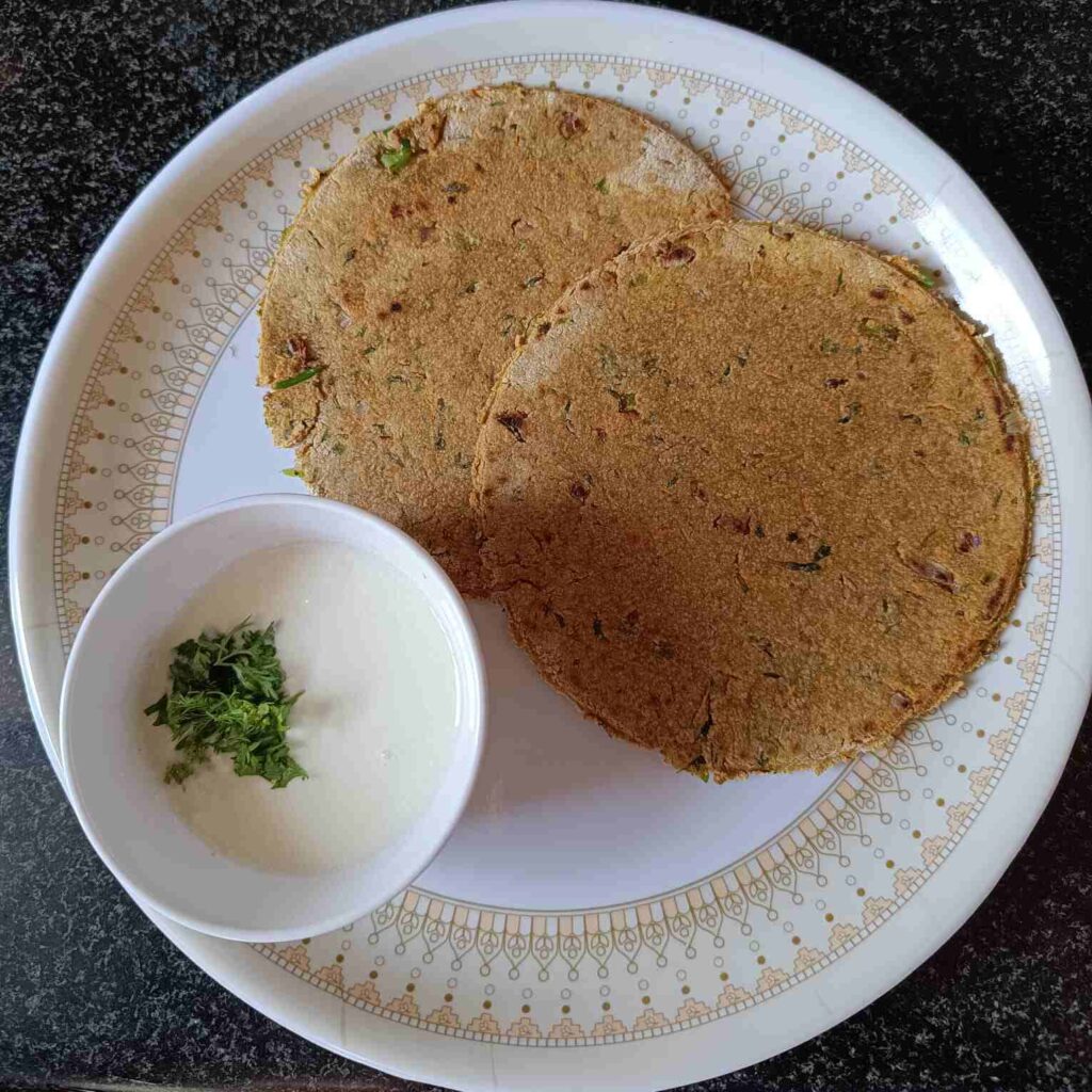 High Protein Indian Breakfast Recipe Oats Paratha and half bowl of curd, showing in a plate