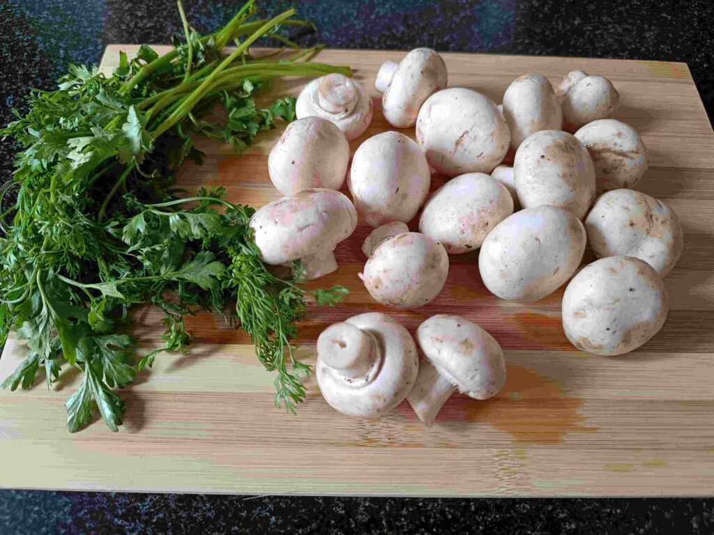 mushrooms and parsley on a cutting board to make chilli mushroom recipe