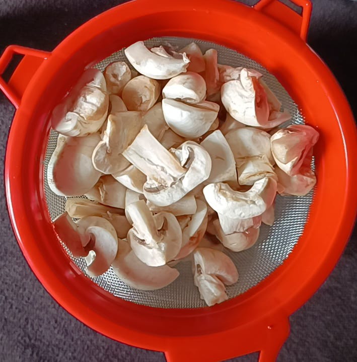 Straining excess water by a strainer for chilli mushroom recipe