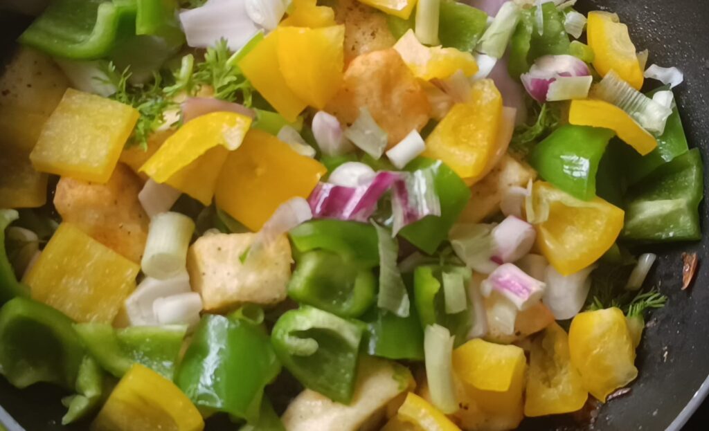 Adding paneer and vegetables like coriander leaves, coriander stems, capsicum, spring onions for veg chilli paneer